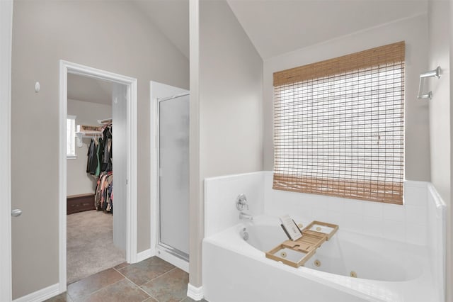 bathroom featuring lofted ceiling, a tub with jets, tile patterned flooring, a spacious closet, and a shower stall