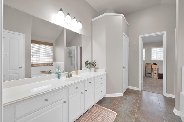 bathroom featuring lofted ceiling, tile patterned floors, baseboards, and vanity