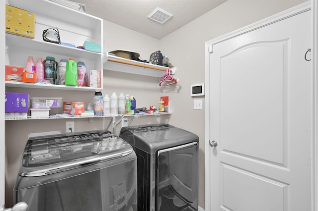 laundry room featuring washing machine and dryer, laundry area, visible vents, and a textured ceiling