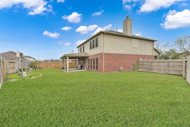 rear view of property featuring brick siding, a chimney, a lawn, a patio area, and a fenced backyard