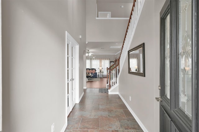 entrance foyer featuring baseboards, a towering ceiling, stairs, stone tile flooring, and french doors