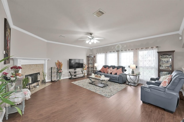 living area with a fireplace, wood finished floors, visible vents, baseboards, and ornamental molding