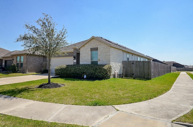 view of front of home featuring an attached garage, fence, driveway, stone siding, and a front yard