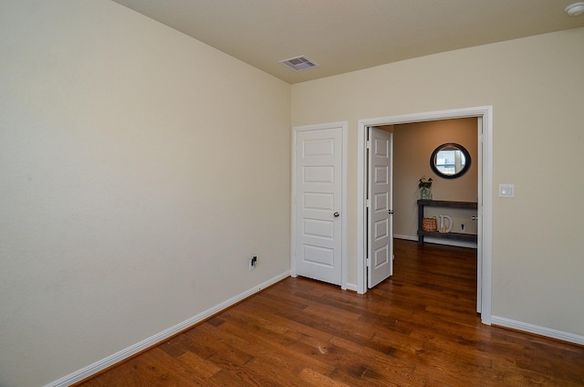 spare room featuring baseboards, visible vents, and dark wood finished floors