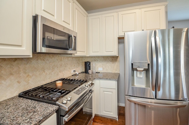 kitchen with appliances with stainless steel finishes, backsplash, white cabinets, and light stone countertops