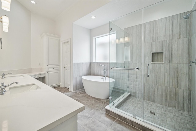 full bath featuring a shower stall, a soaking tub, double vanity, and a sink