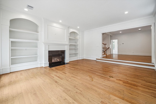 unfurnished living room featuring visible vents, built in shelves, a fireplace with flush hearth, stairs, and light wood-type flooring