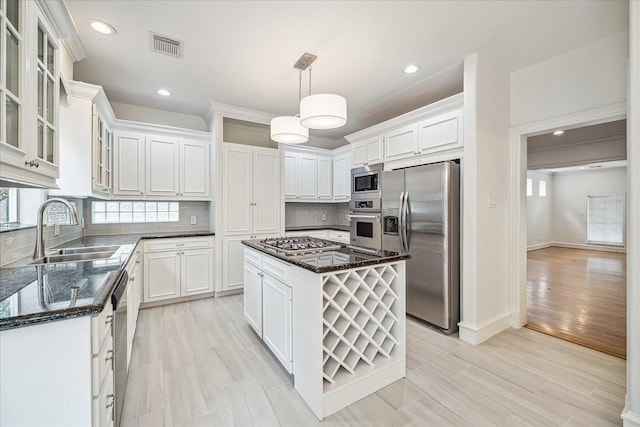 kitchen with tasteful backsplash, dark stone counters, appliances with stainless steel finishes, white cabinets, and a sink