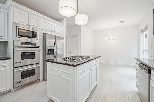 kitchen featuring visible vents, a center island, dark stone counters, appliances with stainless steel finishes, and white cabinetry