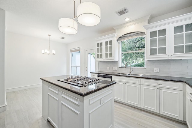 kitchen featuring visible vents, backsplash, a center island, stainless steel gas cooktop, and a sink