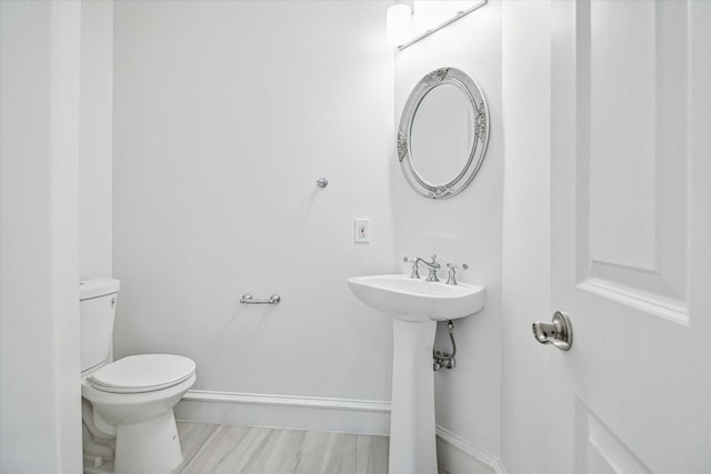 bathroom featuring a sink, baseboards, toilet, and wood finished floors