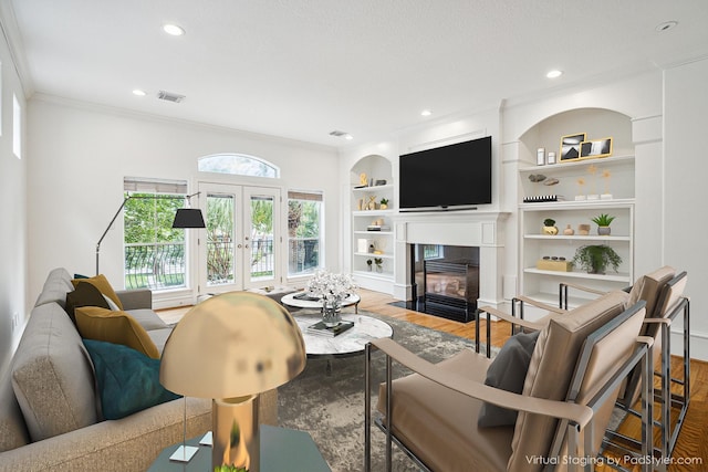 living room featuring built in features, wood finished floors, visible vents, and a fireplace with flush hearth