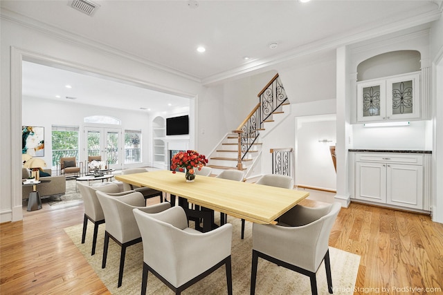 dining space with stairway, visible vents, light wood finished floors, and ornamental molding