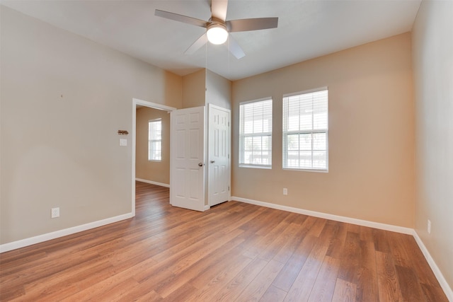 spare room featuring ceiling fan, light wood-type flooring, a wealth of natural light, and baseboards