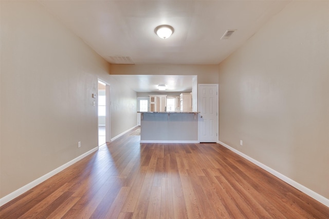 unfurnished living room featuring visible vents, baseboards, and wood finished floors