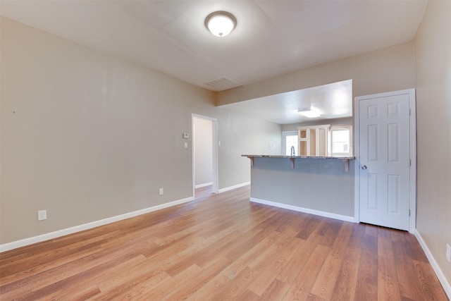 unfurnished room featuring light wood-style flooring, visible vents, and baseboards