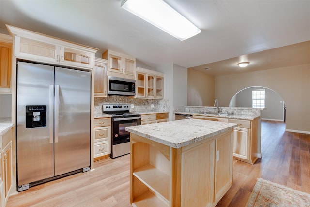 kitchen featuring light wood-type flooring, appliances with stainless steel finishes, a sink, and light brown cabinetry