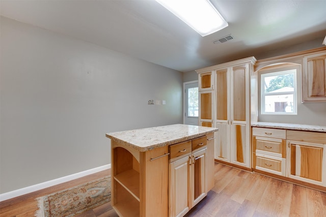 kitchen featuring baseboards, light countertops, a kitchen island, and light wood-style floors