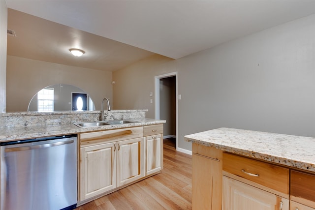 kitchen with arched walkways, stainless steel dishwasher, light wood-style floors, a sink, and light stone countertops