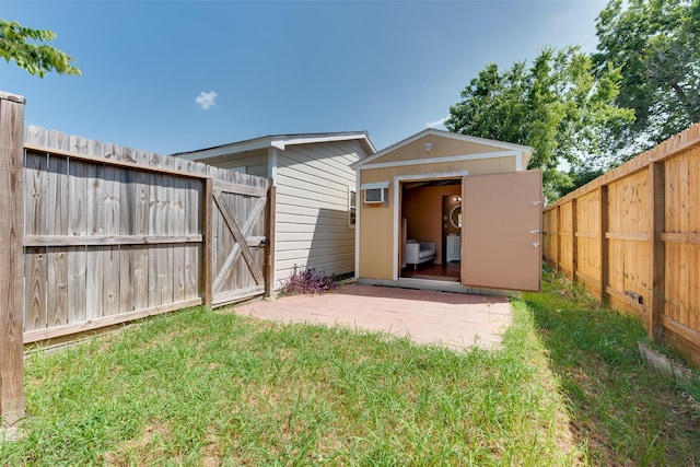 back of house featuring an outbuilding, a fenced backyard, a lawn, a gate, and a storage unit