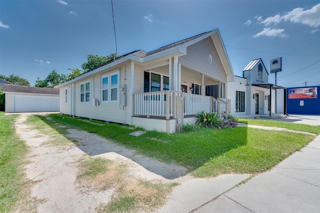 bungalow with a porch, an outdoor structure, and dirt driveway