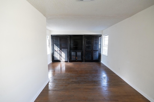 unfurnished room featuring a textured ceiling, baseboards, and wood finished floors