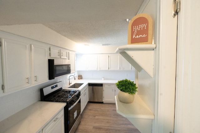 kitchen featuring appliances with stainless steel finishes, light countertops, white cabinets, and a sink