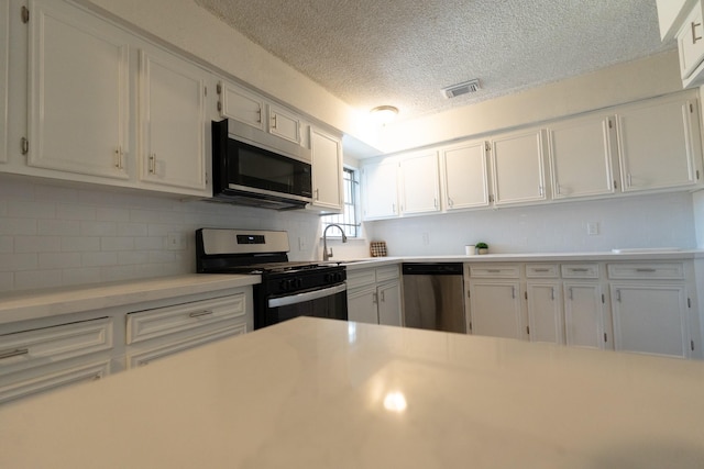 kitchen featuring stainless steel appliances, a sink, visible vents, white cabinetry, and light countertops