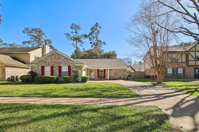 view of front of home featuring brick siding, a chimney, concrete driveway, fence, and a front lawn