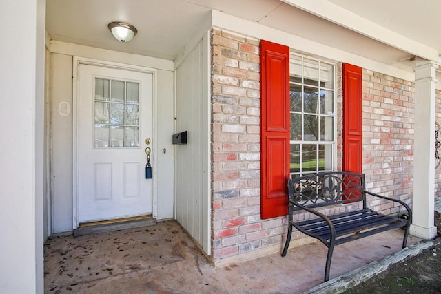 view of exterior entry with covered porch and brick siding