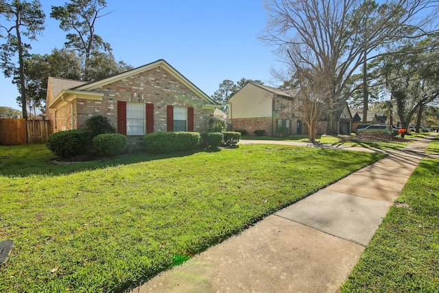 view of front of house with brick siding, a front yard, and fence