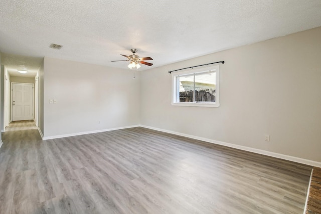 unfurnished room with visible vents, a textured ceiling, baseboards, and wood finished floors