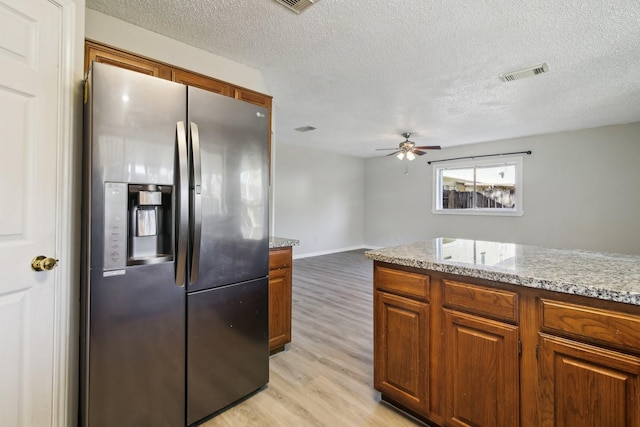 kitchen featuring light wood-style flooring, brown cabinets, visible vents, and stainless steel fridge with ice dispenser