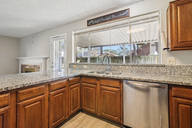 kitchen featuring a fireplace, a sink, a textured ceiling, light wood-type flooring, and dishwasher