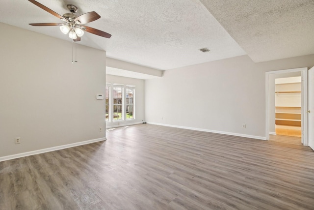 unfurnished living room featuring a textured ceiling, baseboards, and wood finished floors