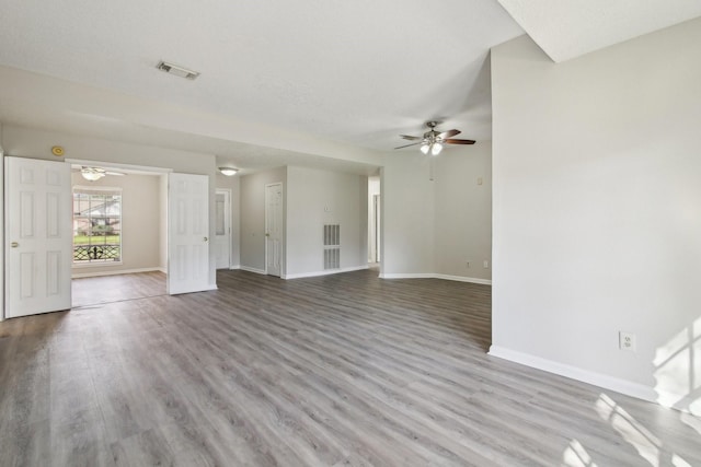 unfurnished living room featuring baseboards, visible vents, and wood finished floors