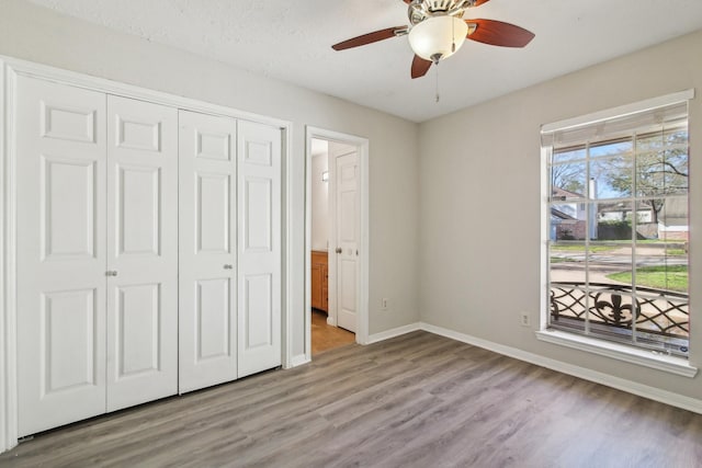 unfurnished bedroom featuring ensuite bathroom, a closet, wood finished floors, and baseboards