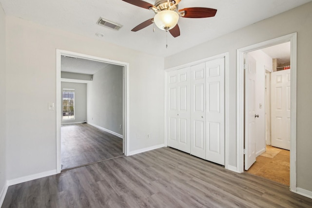 unfurnished bedroom featuring a closet, visible vents, baseboards, and wood finished floors