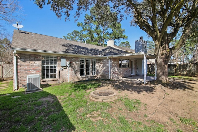 rear view of house with a fire pit, central AC unit, fence, and brick siding