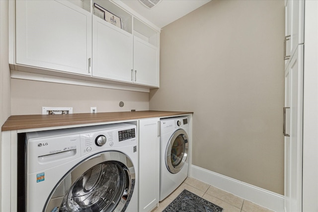 laundry area featuring light tile patterned floors, cabinet space, baseboards, and separate washer and dryer