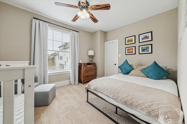 bedroom with light carpet, ceiling fan, and baseboards