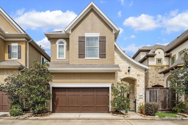 view of front facade with a garage, driveway, fence, and stucco siding