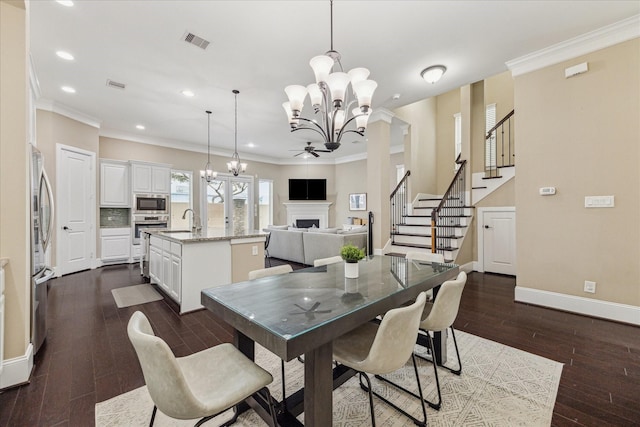 dining room with an inviting chandelier, a fireplace, visible vents, and crown molding