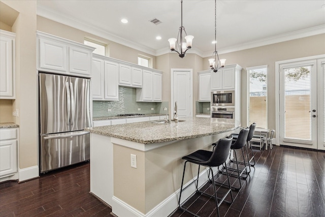 kitchen featuring stainless steel appliances, dark wood-style flooring, a sink, visible vents, and backsplash