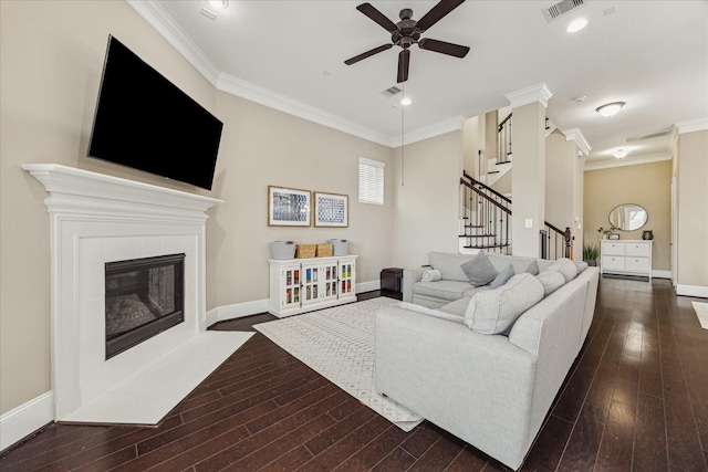 living area featuring a tiled fireplace, dark wood finished floors, visible vents, and crown molding