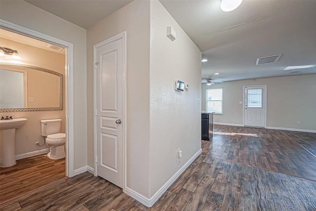 corridor with a sink, dark wood finished floors, and visible vents