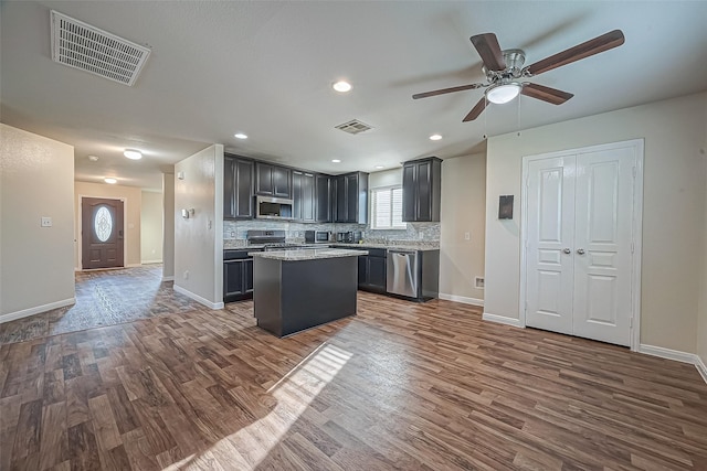 kitchen featuring appliances with stainless steel finishes, visible vents, dark wood finished floors, and tasteful backsplash