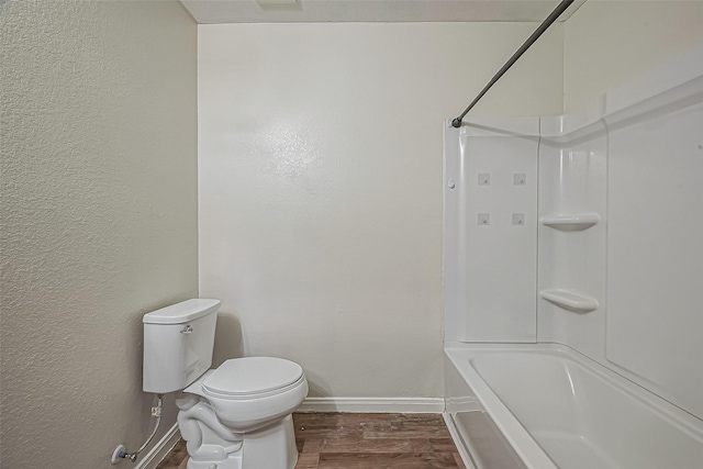 bathroom with shower / bathtub combination, a textured wall, toilet, wood finished floors, and baseboards