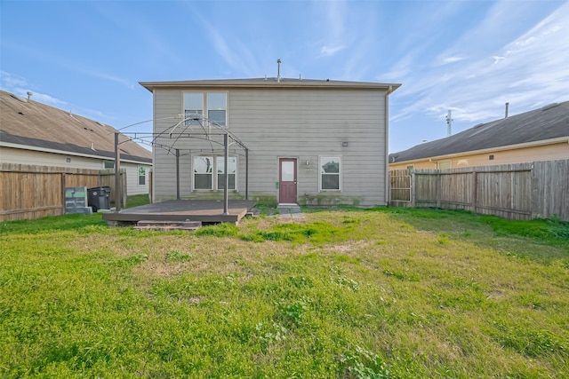 rear view of house with a fenced backyard and a lawn