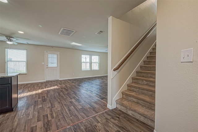 interior space featuring stairway, baseboards, visible vents, and dark wood finished floors